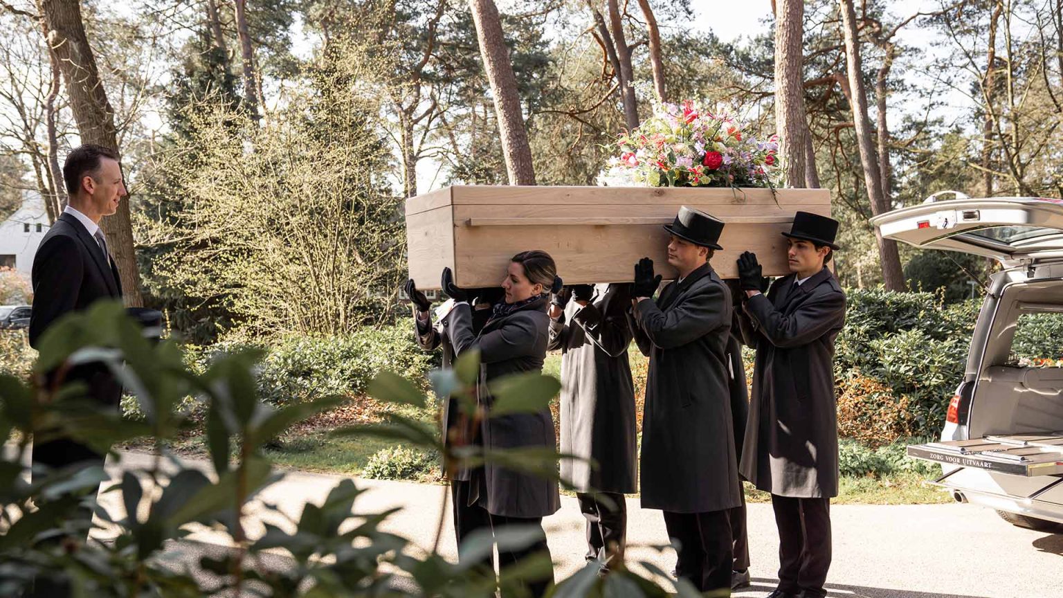 Uitvaartmedewerkers dragen een kist tijdens een begrafenis
